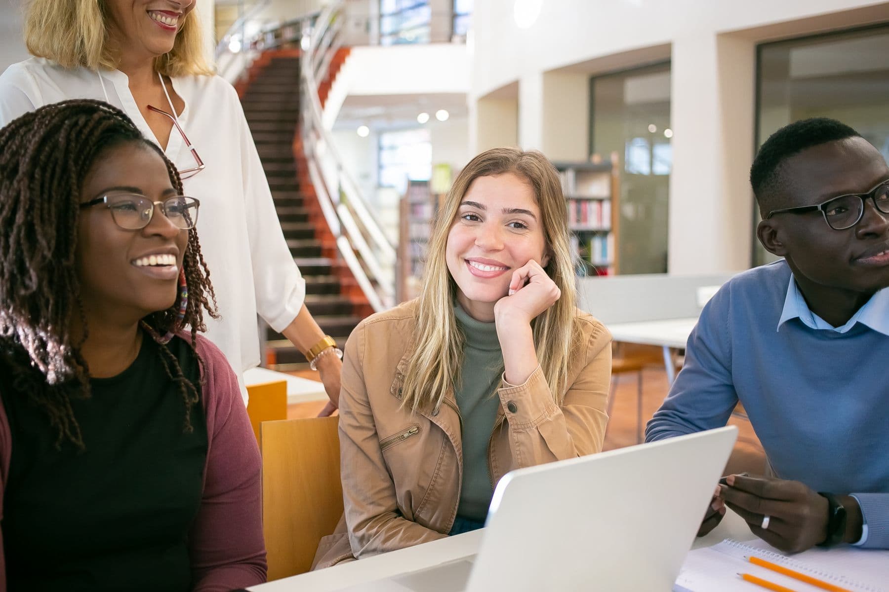 A group of adult learners with a tutor in a library study space