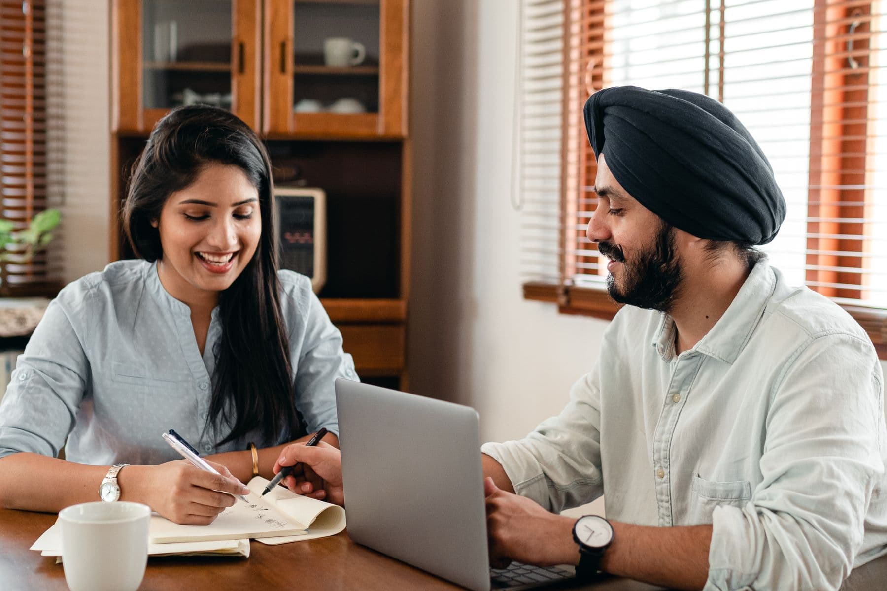 Two adults working together with a notebook and laptop