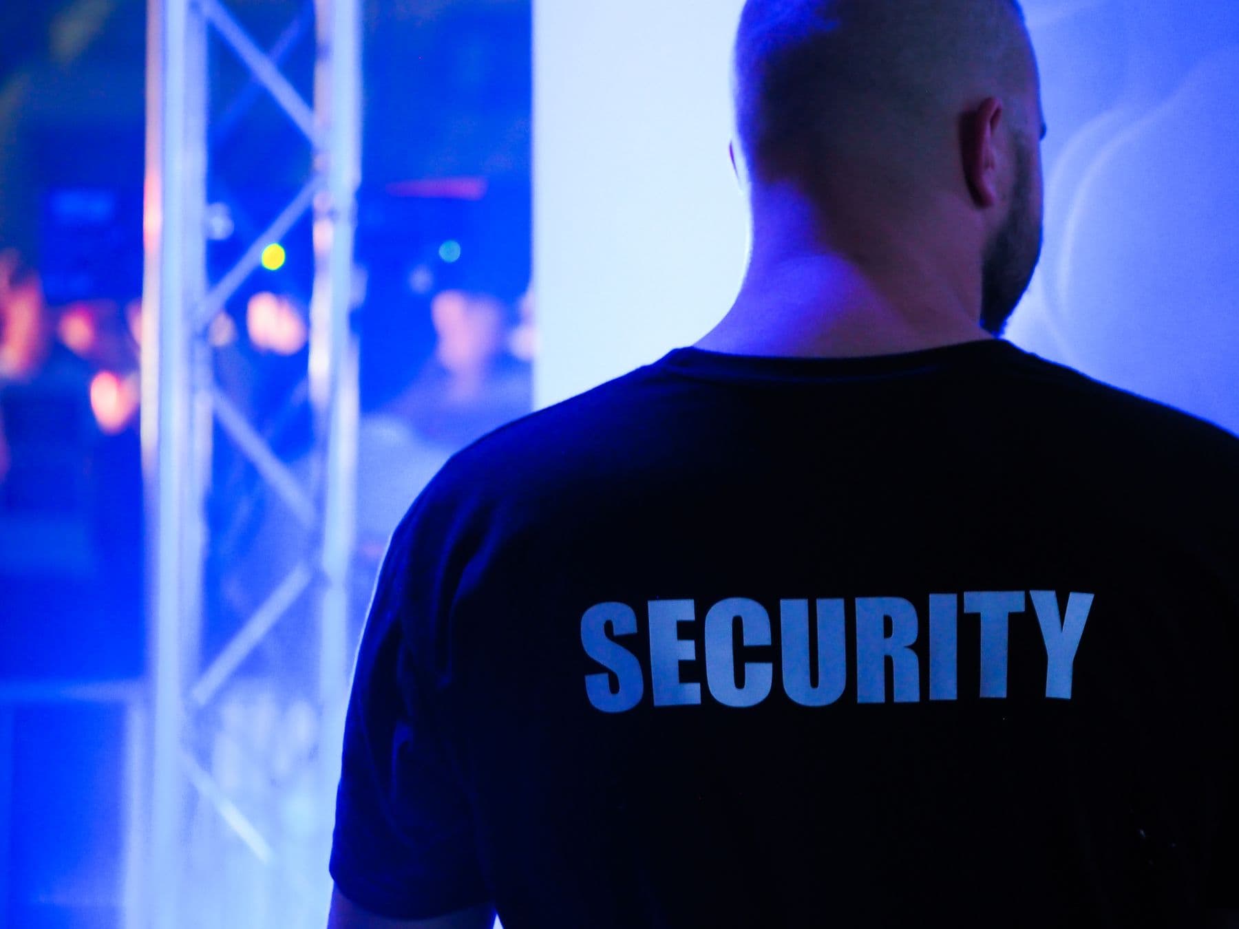 A security steward in a black SECURITY shirt at a live event