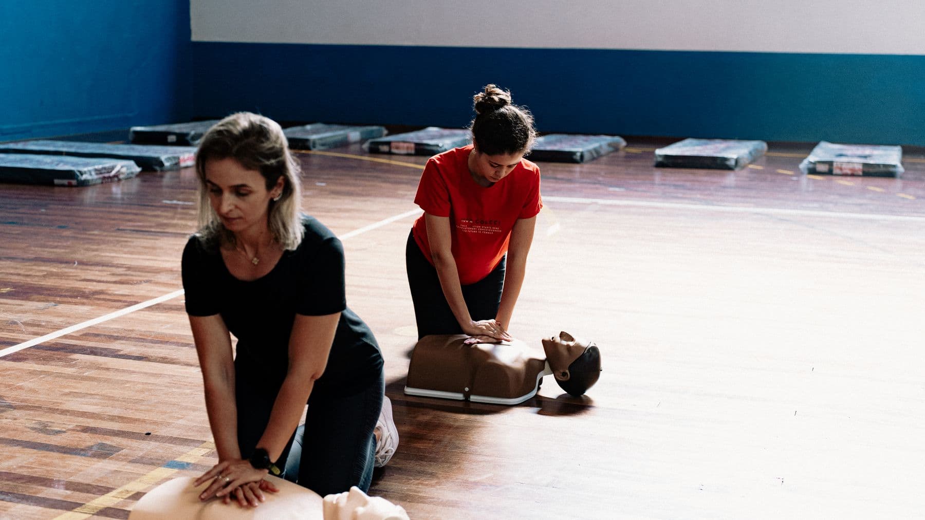 Learners practising CPR on training manikins in a hall