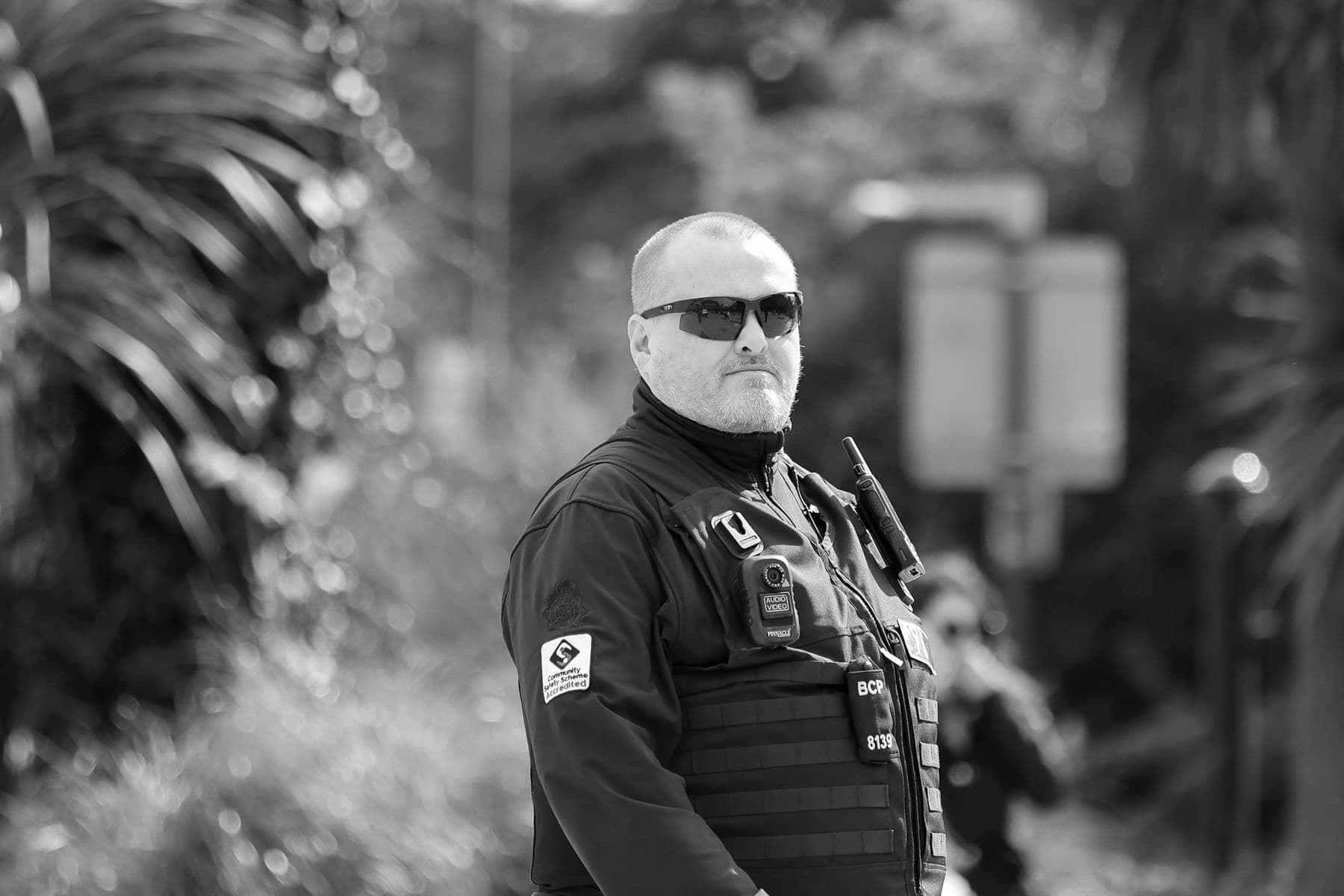 A uniformed security officer with a radio and body-worn camera